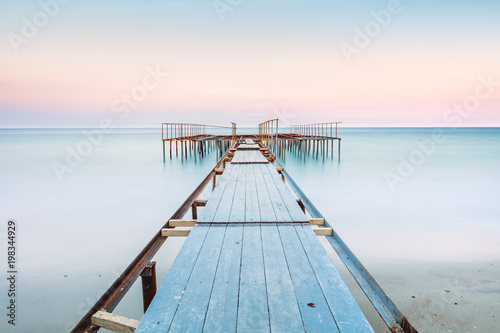 Fotografia Long esposure view of a old jetty in a calm sea with gentle sky, soft colors