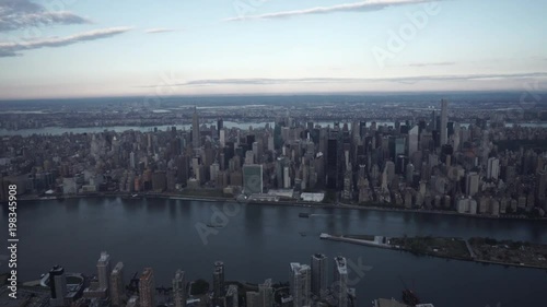New York City wide angle aerial view of Midtown Manhattan skyline and Central Park from Long Island City, flying over the East River and the Queensboro Bridge.