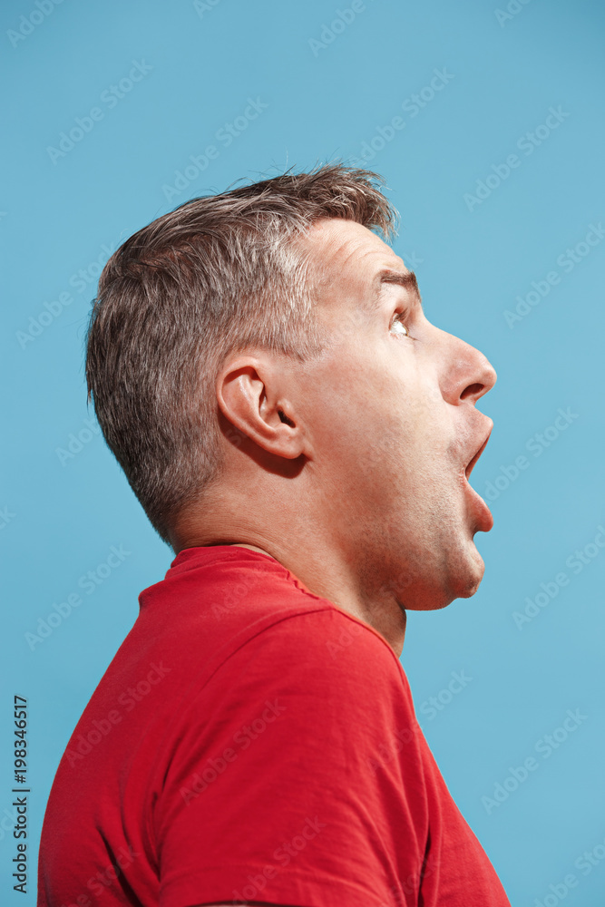 Obraz premium The young attractive man looking suprised isolated on blue