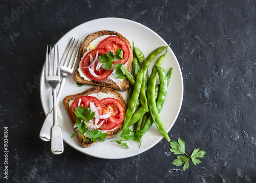 Tomato and cheese sandwiches and green beans - healthy vegetarian snack on a dark table, top view
