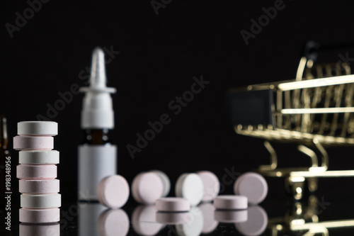 Medications and a gold shopping cart in the concept of expensive medicine. With copy space.