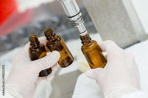 Close up of female lab worker hand with gloves filling the bottle with syrup