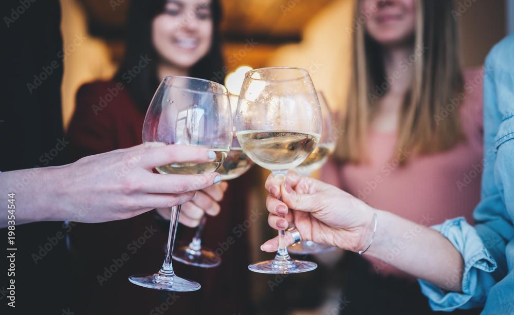 Happy friends cheering with glasses of white wine at home, group of people making a toast and celebrating anniversary, enjoyment and celebrating concept, lifestyle