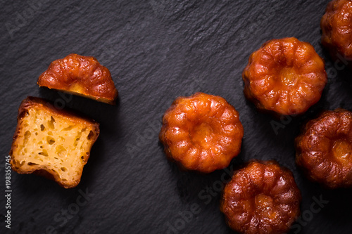 French pastry Canele rum and vanilla flavor thick caramelized crust on black slate plate photo