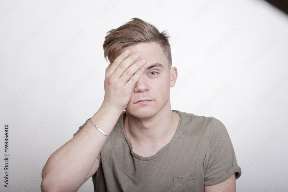 Mann hält sich beim Sehtest ein Auge zu Mann hält sich beim Sehtest ein Auge zu