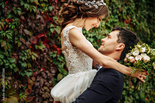 Bride holds her veil on her hand while she hugs groom