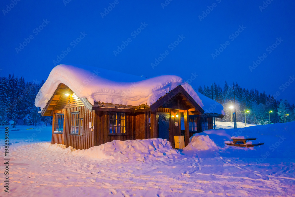 Amazing night view of traditional wooden houses with snow in the roof in stunning nature background in Valdres region in Norway