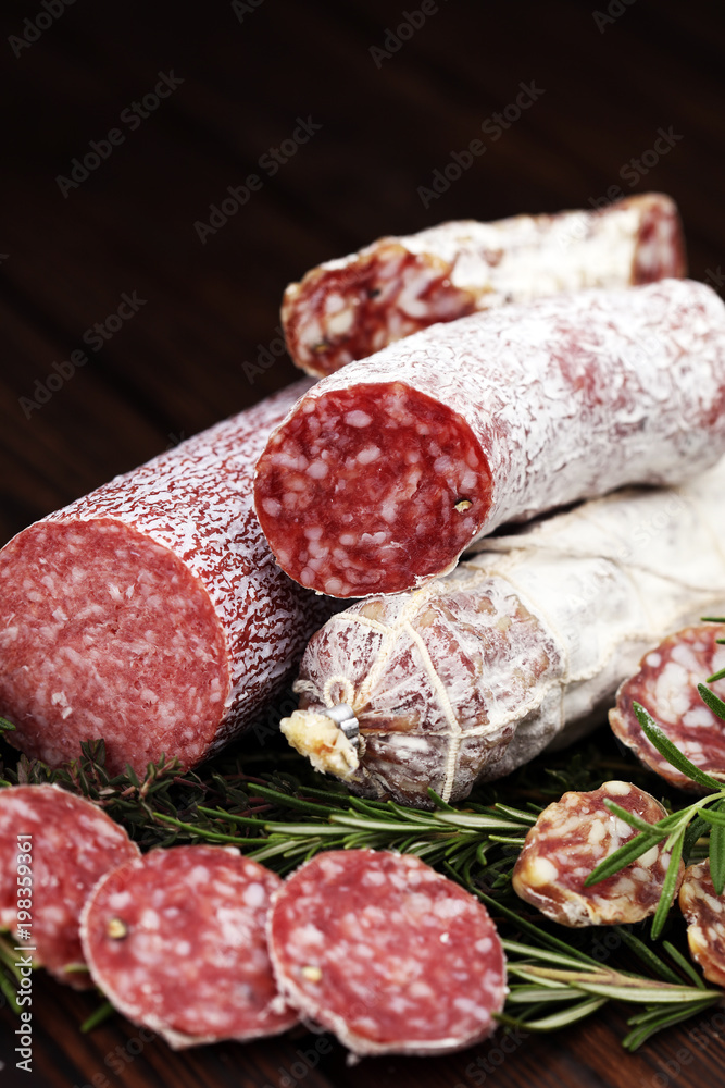 thinly sliced salami on a wooden texture on the background. thinly sliced salami on a wooden texture on the background.
