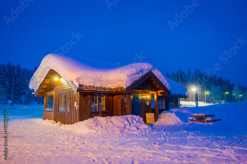 Amazing night view of traditional wooden houses with snow in the roof in stunning nature background in Valdres region in Norway photo