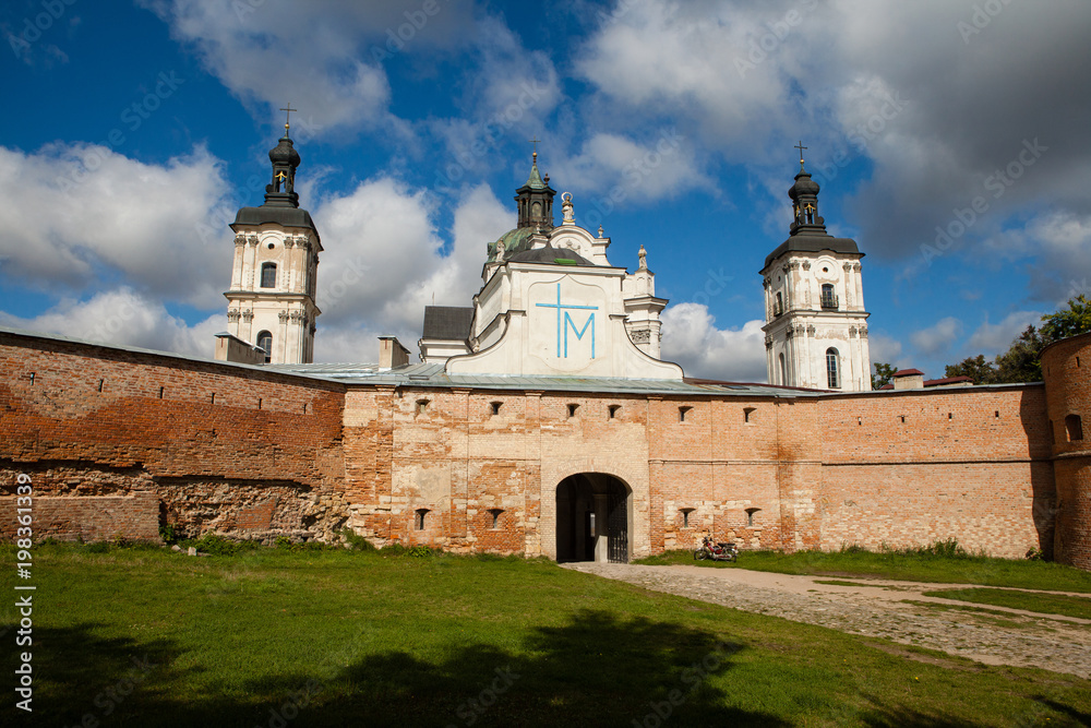 Ancient monastery of Discalced Carmelites, cathedral and fortress wall on background of blue cloudy sky. Berdychiv, Ukraine. Tourist attraction. Place of visit by Pope John Paul II