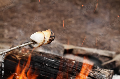 Two toasted marshmallows on a stick over a bonfire at the camp grounds.