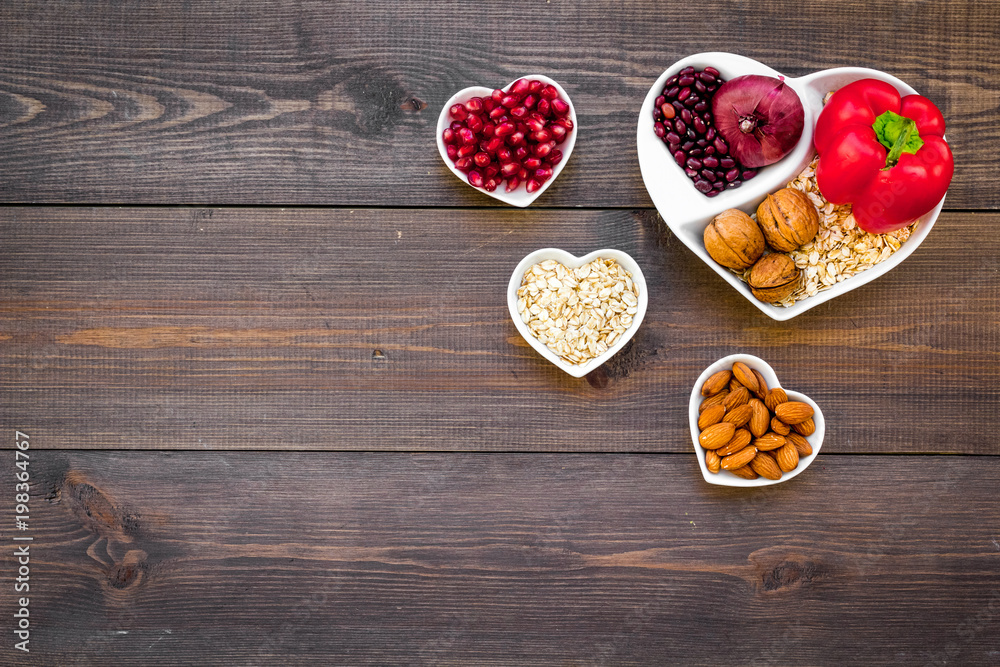 Food which help heart stay healthy. Vegetables, fruits, nuts in heart shaped bowl on dark wooden background top view copy space Food which help heart stay healthy. Vegetables, fruits, nuts in heart shaped bowl on dark wooden background top view copy space