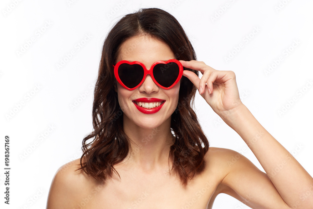 valentines day, beauty and people concept - happy smiling young woman with red lipstick and heart shaped sunglasses over white background valentines day, beauty and people concept - happy smiling young woman with red lipstick and heart shaped sunglasses over white background