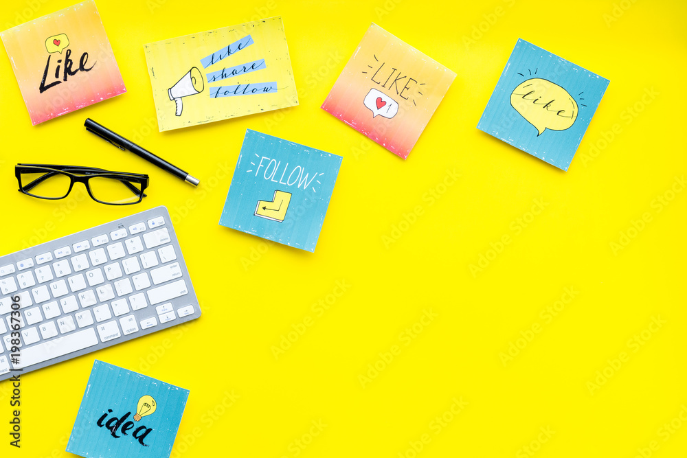 Socail media icons on work desk of marketing expert. Digital promotion of goods and services. Yellow background top view copy space Socail media icons on work desk of marketing expert. Digital promotion of goods and services. Yellow background top view copy space