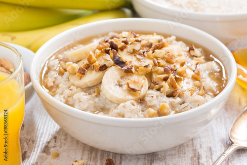 healthy breakfast - oatmeal with banana, honey and walnuts in a bowl
