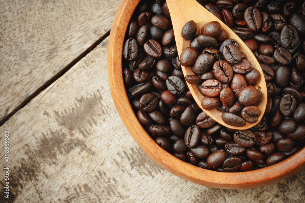 Fototapeta premium top view coffee beans in wooden spoon on the wooden table.copy space.
