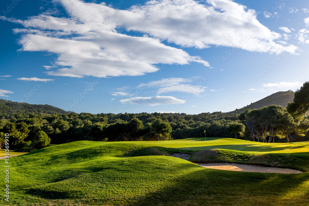 Obraz premium Golf course on sunset with green grass, blue sky and clouds. Photo taken in Spain at the La Manga Club. 