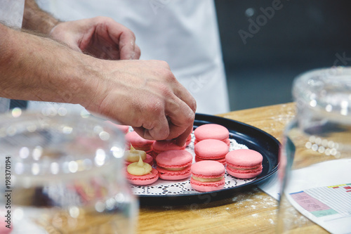 фотографія chef with macaroons on tray at bakery