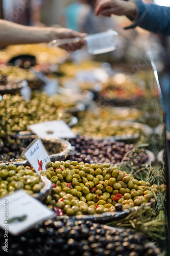 mixed olives on display in market with vendor filling a box in the background
