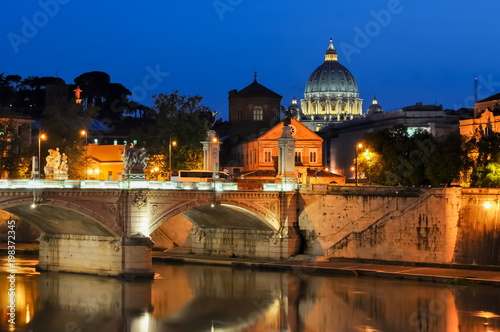 Night view of Victor Emmanuel bridge over Tiber river with St. Peter's Cathedral dome at background, Rome, Italy