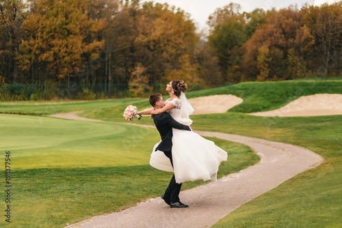 Young happy wedding couple are dance on the green grass field