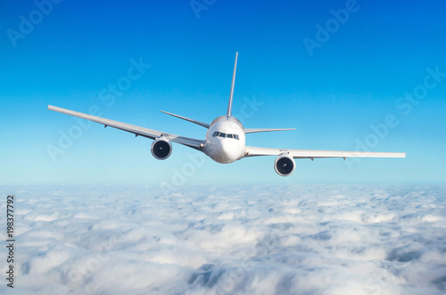 Passenger airplane flying at flight level high in the sky above the clouds. View directly in front  exactly.