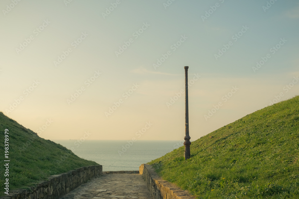 the sea on the horizon at golden sunset with street lamp