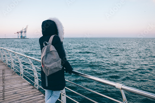 Young woman in the hood looking at the winter sea © progressman