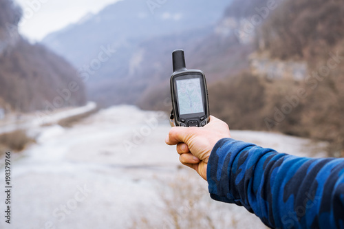 Hand held outdoor GPS being used for navigation in the mountains on the background of the river