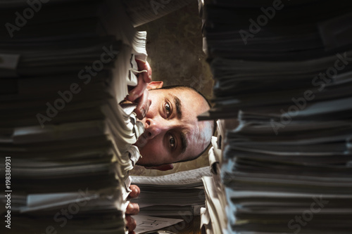 the face of a tired clerk, peeks out of the bundle of documents.in the style of horror