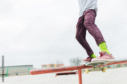 A close-up of a teenager's leg of a skateboarder glides on a skateboard along the railing in the skatepark. The concept of moving forward at a young age. Teenage Sports