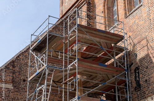 scaffolding / Scaffolding in front of the wall of a gothic brick church