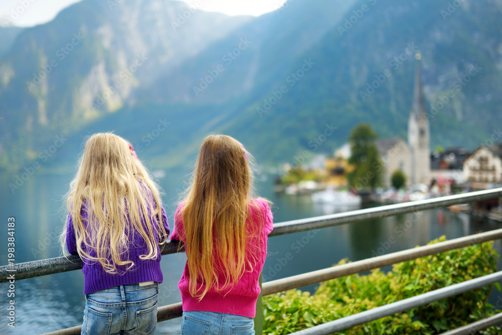 Two girls enjoying the scenic view of Hallstatt lakeside town in the Austrian Alps in beautiful evening light on beautiful day in autumn