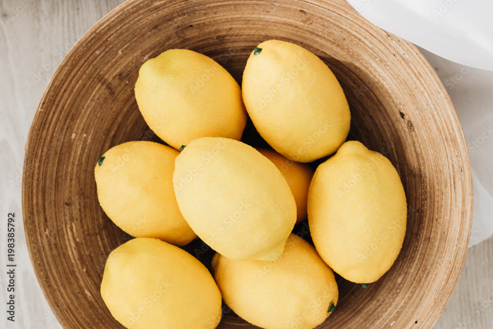 Pile of fresh lemons in wooden bowl