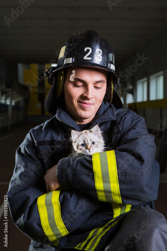 firefighter plays with a kitten, hugs, rejoices
