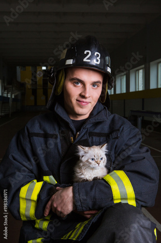 firefighter plays with a kitten, hugs, rejoices