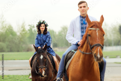 The girlfriend and boyfriend are horse riding and looking at the camera lens