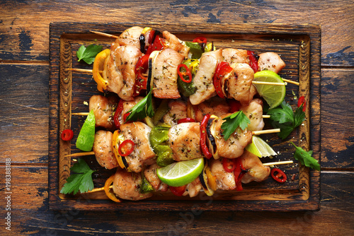 Grilled chicken kebab (skewers) with vegetables on a cutting wooden board.Top view .
