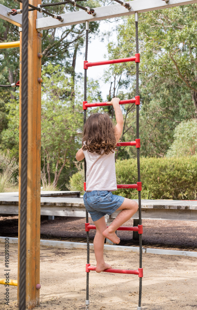 Little girl in blue shorts climbing rope ladder at playground in natural  bushland setting (selective focus) Photos | Adobe Stock