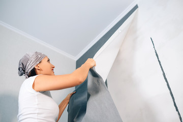 Woman take of wallpapers from wall