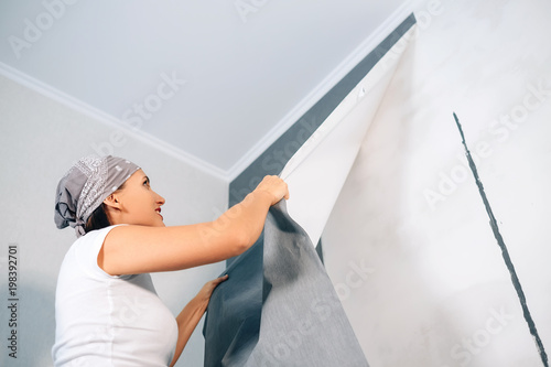 Obraz na plátne Woman take of wallpapers from wall
