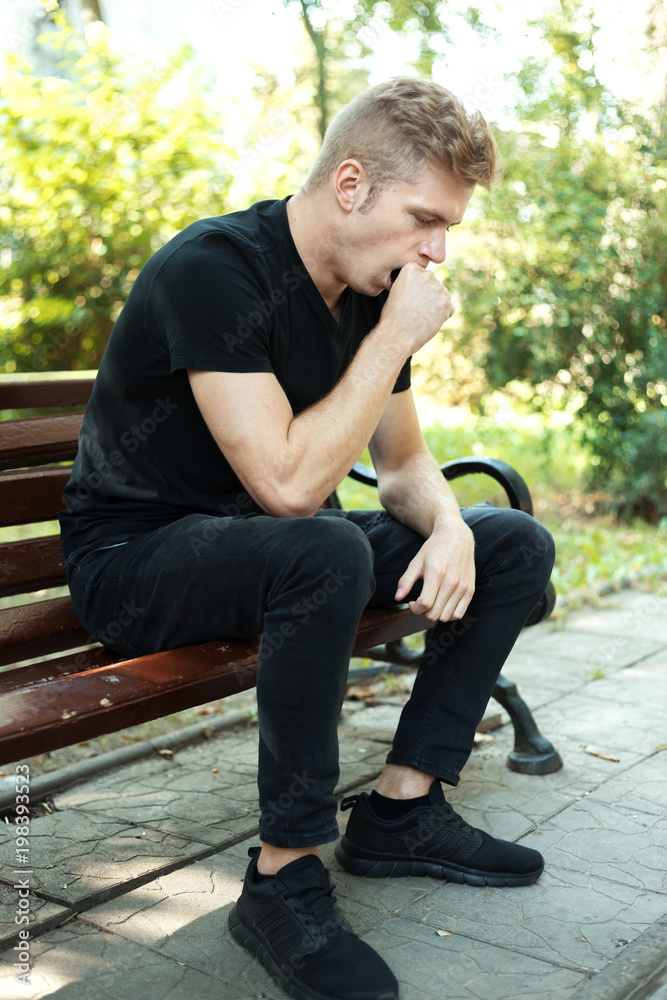 Tired young man are siting on a bench in the park Tired young man are siting on a bench in the park