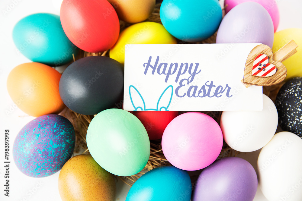 Multi-colored Easter eggs in nest on wooden background, selective focus image. Happy Easter card 