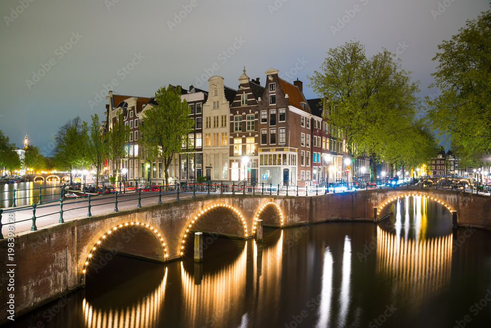 Obraz premium Amsterdam canal, bridge and typical houses during evening twilight blue hour