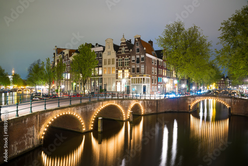 Amsterdam canal, bridge and typical houses during evening twilight blue hour