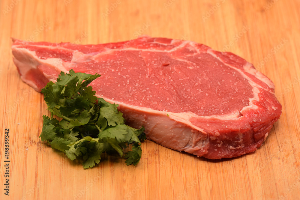 Tenderized steak with salt crystals on wooden cutting board. Tenderized steak with salt crystals on wooden cutting board.