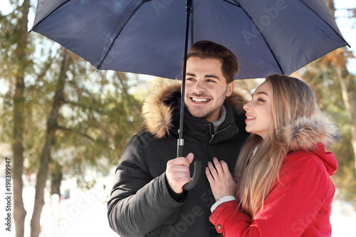 Young romantic couple with umbrella in park