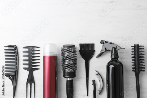 Flat lay composition with professional hairdresser tools on wooden background