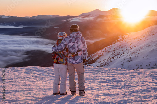 Couple enjoying the beauty of sunset at snowy ski resort. Winter vacation