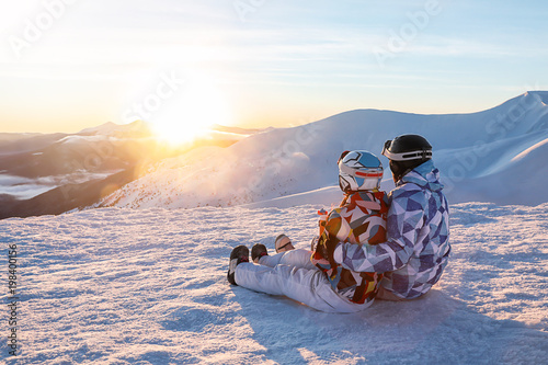 Couple enjoying the beauty of sunset at snowy ski resort. Winter vacation